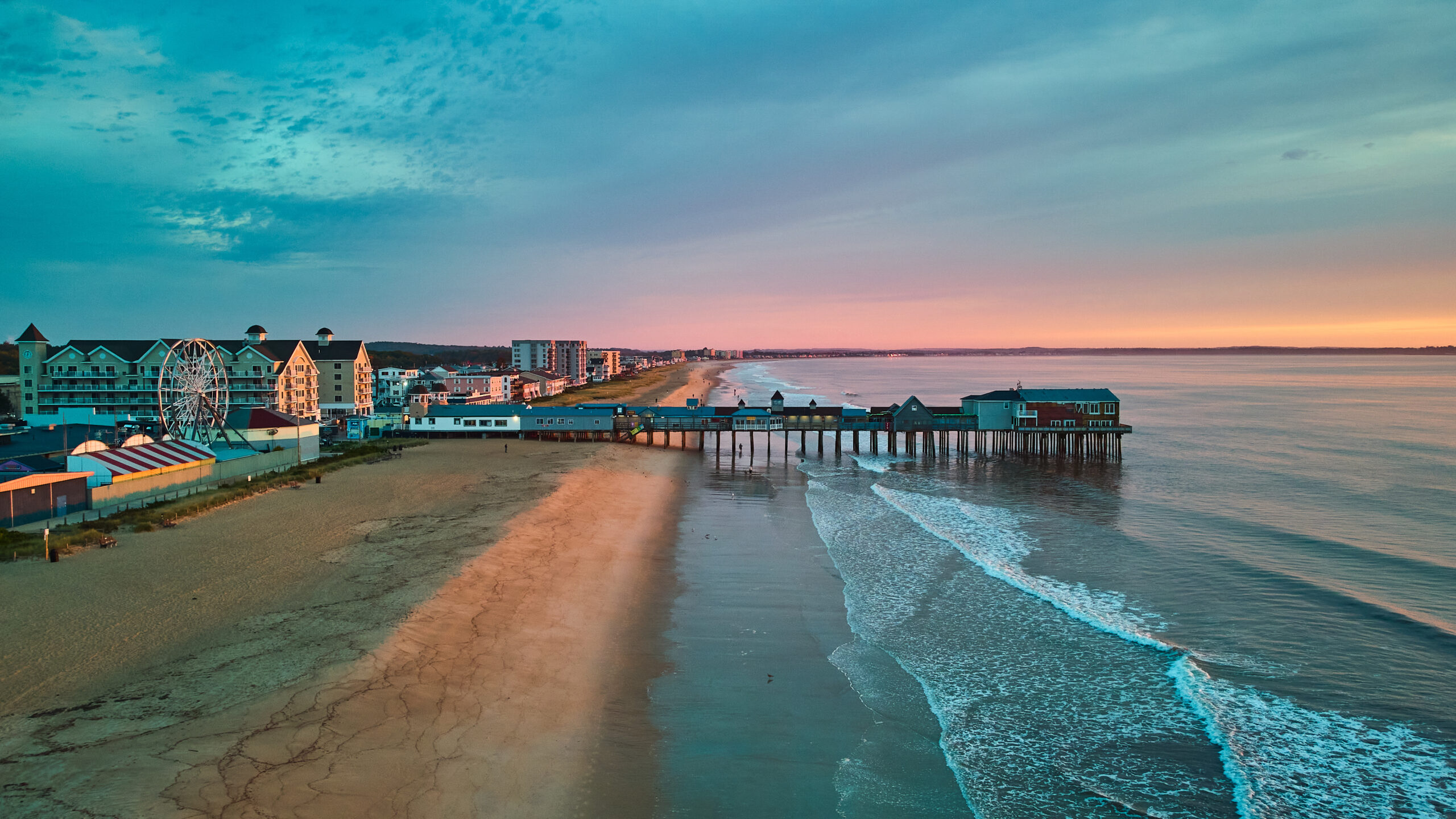 Image of Aerial view over beach in Maine during sunrise with town and old wood pier of shops